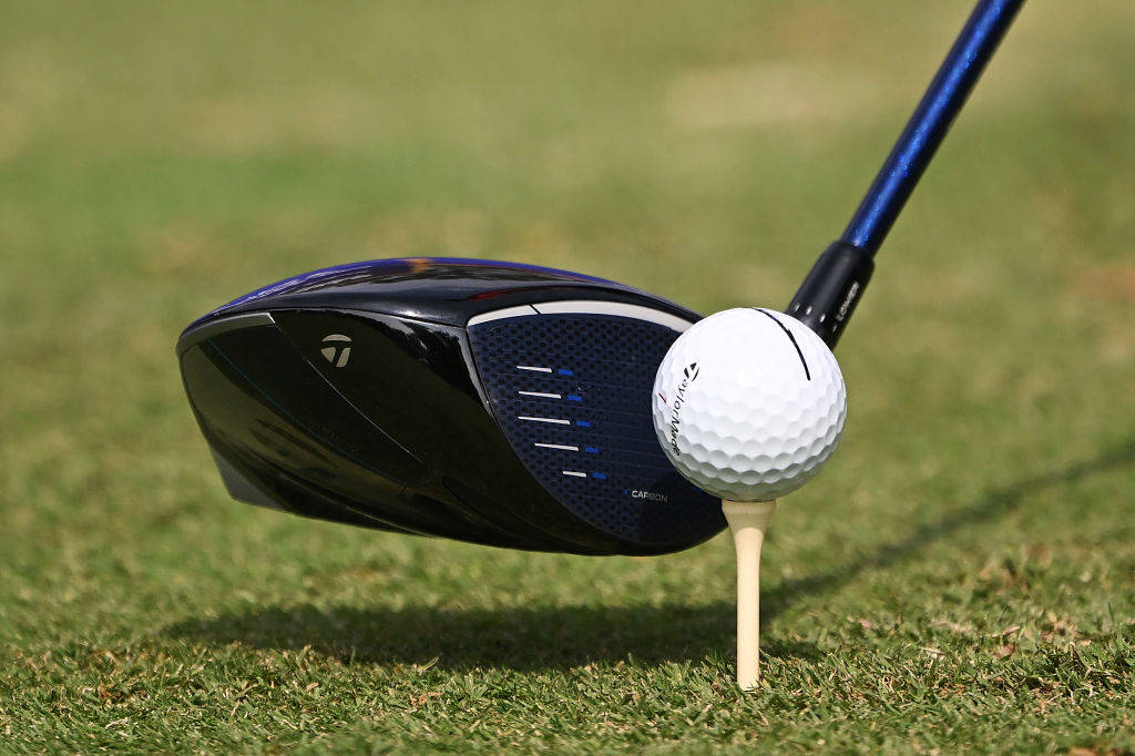 A driver addressing a golf ball and tee